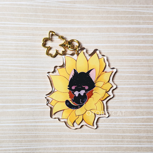 Black Cat Keychain - A stunning keychain featuring a black cat gracefully resting on a sunflower. This unique and elegant keychain is perfect for cat lovers and adds a touch of nature-inspired beauty to your daily essentials. Order your black cat keychain today and carry a little feline charm wherever you go!